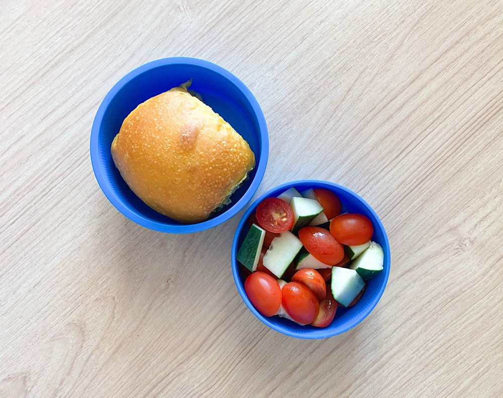 Pote com pãozinho e salada de pepino e tomate